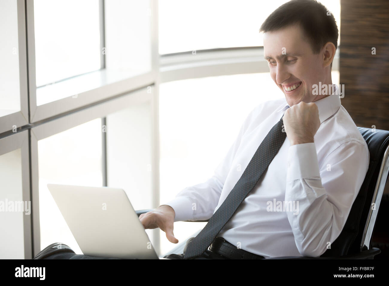 Porträt von fröhlich hübscher junger Geschäftsmann sitzt in seinem Büro mit Technik. Glückliche Unternehmen Unternehmer Stockfoto