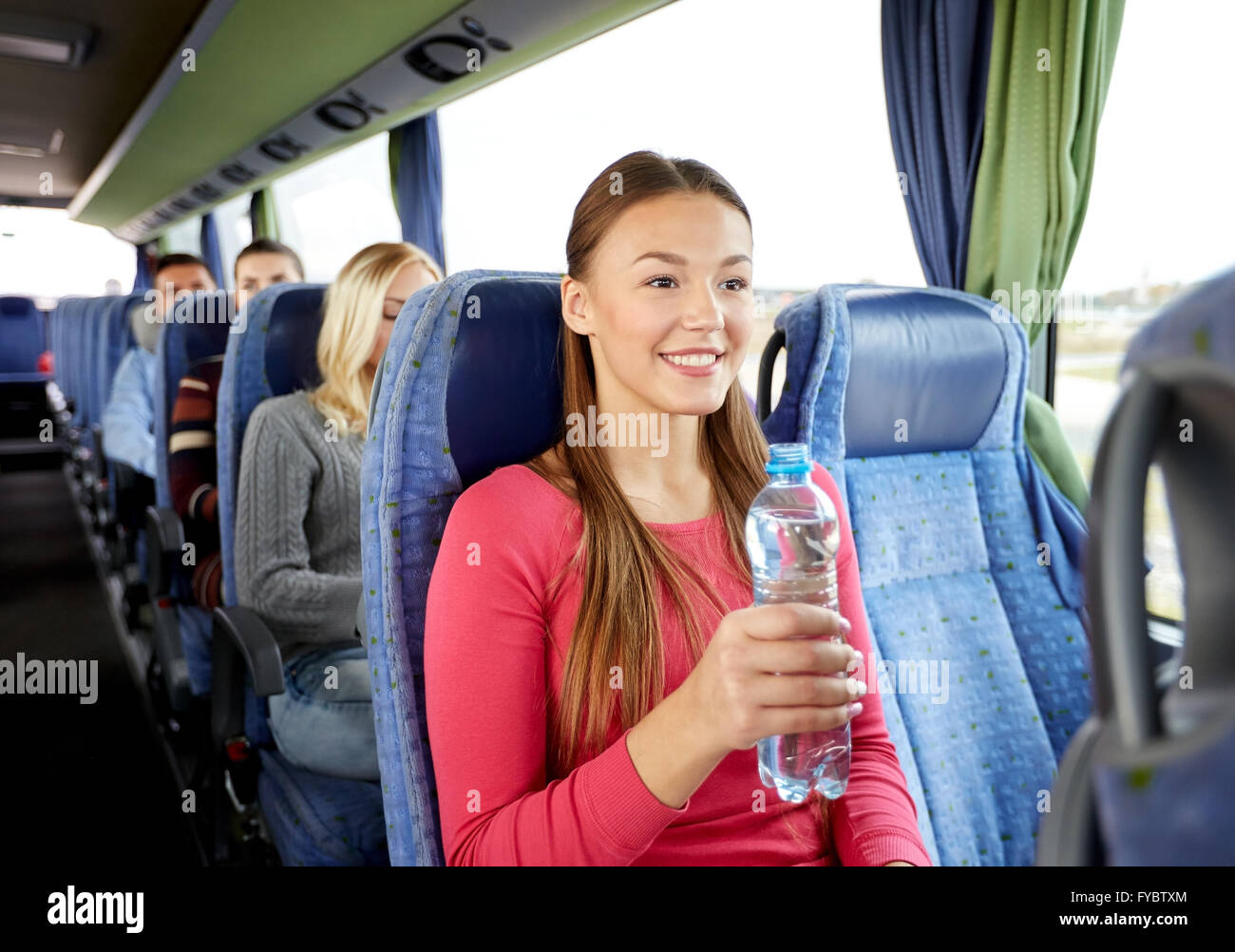 glückliche junge Frau mit Wasserflasche im Reisebus Stockfoto