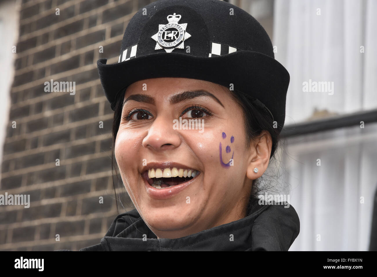 Lächelnd weibliche Gemeinschaft Liaison Polizeioffizier, mit Smiley Malerei auf ihrer Wange, Anti Sparmaßnahmen März, Gower Street, London, UK Stockfoto