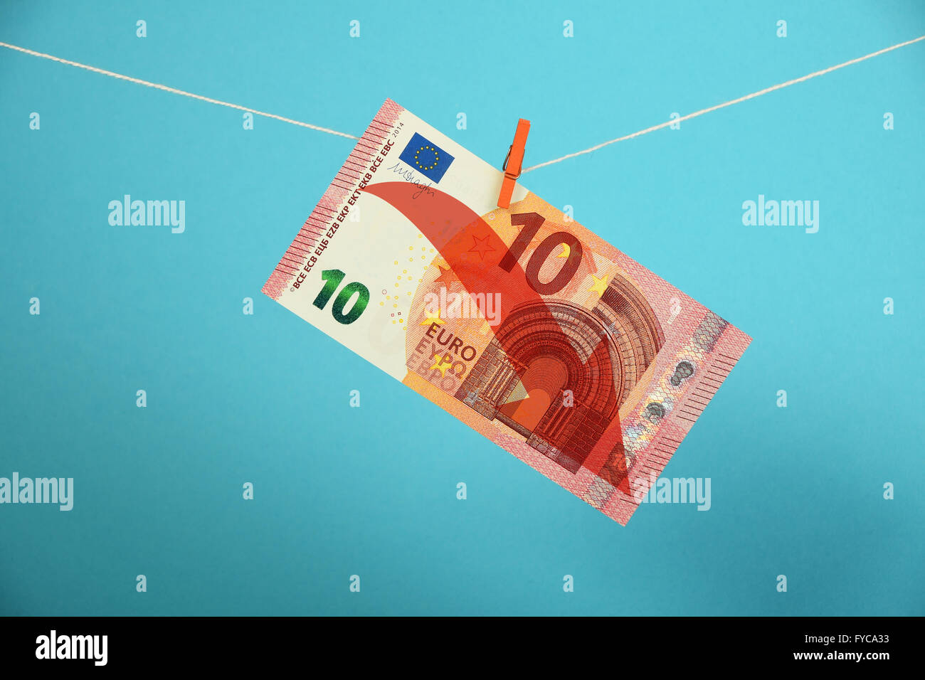 Europäische Wirtschaftskrise, Niedergang des Euro, 10 Euro-Banknote mit roten Pfeil nach unten gehängt absteigend mit Pin am Seil über blaue bac Stockfoto