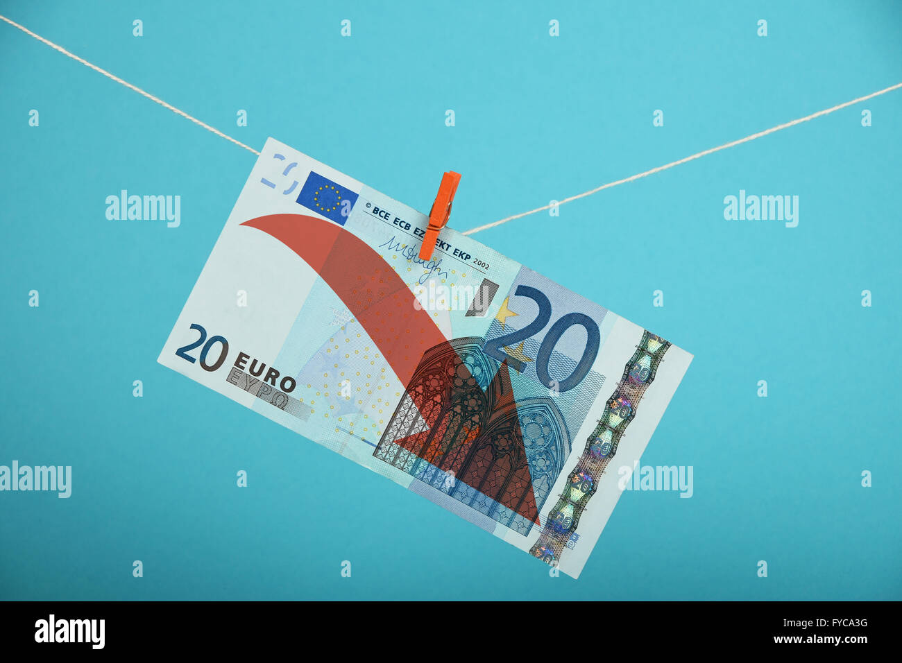 Europäische Wirtschaftskrise, Niedergang des Euro, 20 Euro-Banknote mit roten Pfeil nach unten gehängt absteigend mit Pin am Seil über blau Stockfoto