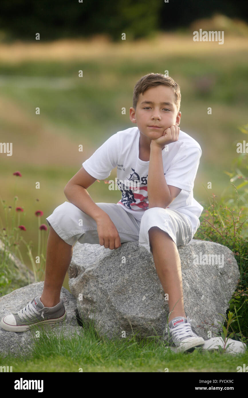 Junge, 9 Jahre alt, sitzt auf Felsen Stockfoto
