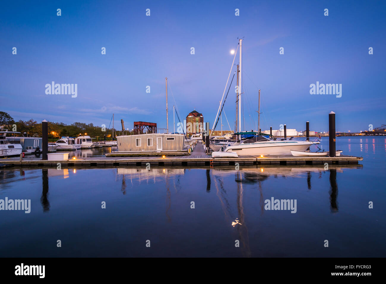 Vollmond über Boote und Docks in der Dämmerung, im Kanton, Baltimore, Maryland. Stockfoto