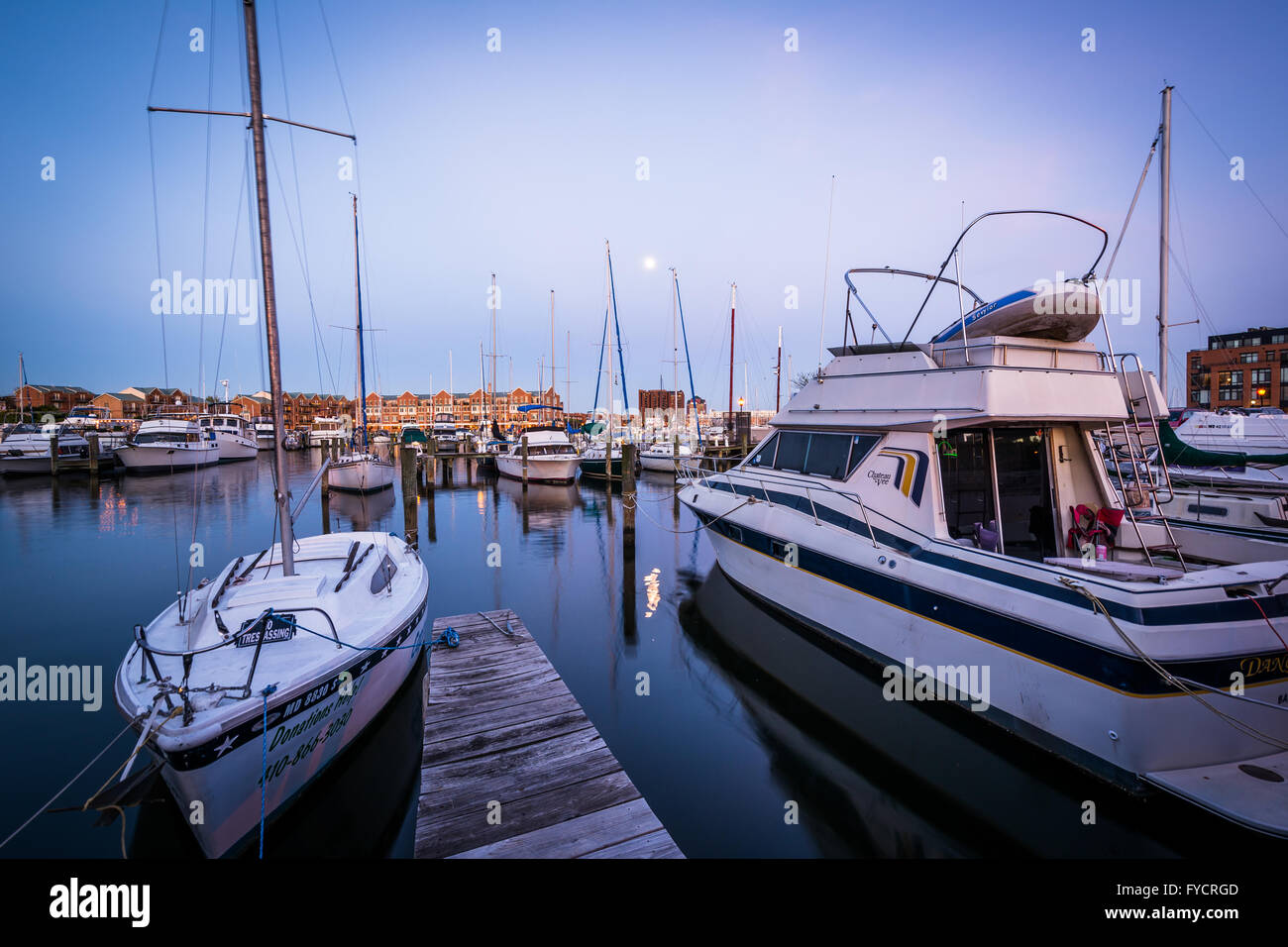 Vollmond über Boote verankert in der Dämmerung, in Fells Point, Baltimore, Maryland. Stockfoto