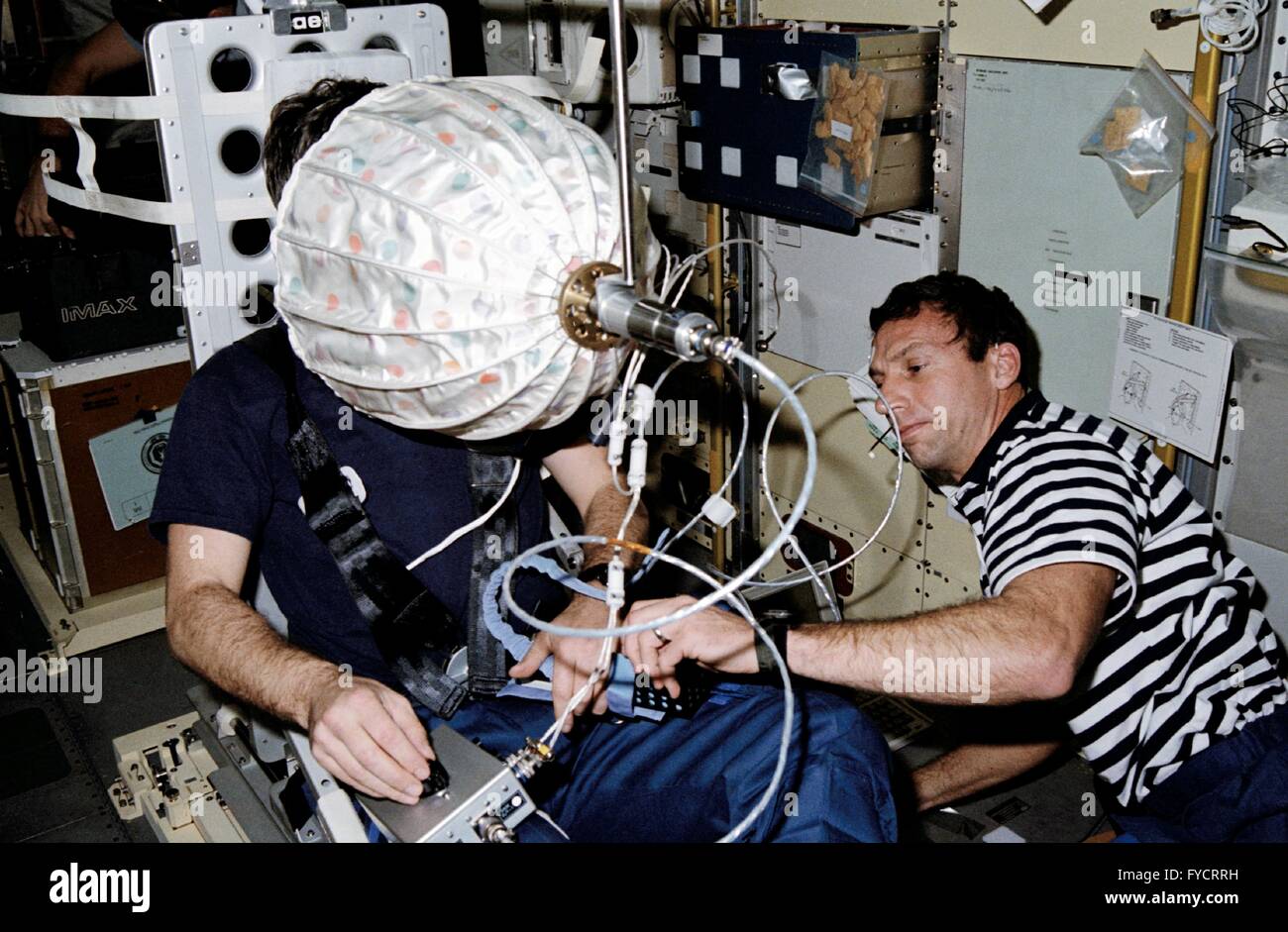 NASA-Astronauten David Hilmers, Recht, unterstützt ESA Astronaut deutsche Ulf Merbold mit dem visuellen Stimulator-Experiment an Bord der Raumfähre Discovery-Mission STS-42 23. Januar 1992 in der Erdumlaufbahn. Stockfoto