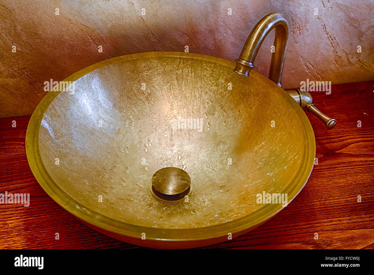 Waschbecken im goldenen Blatt aus gehärtetem Glas und Messing Wasserhahn Stockfoto