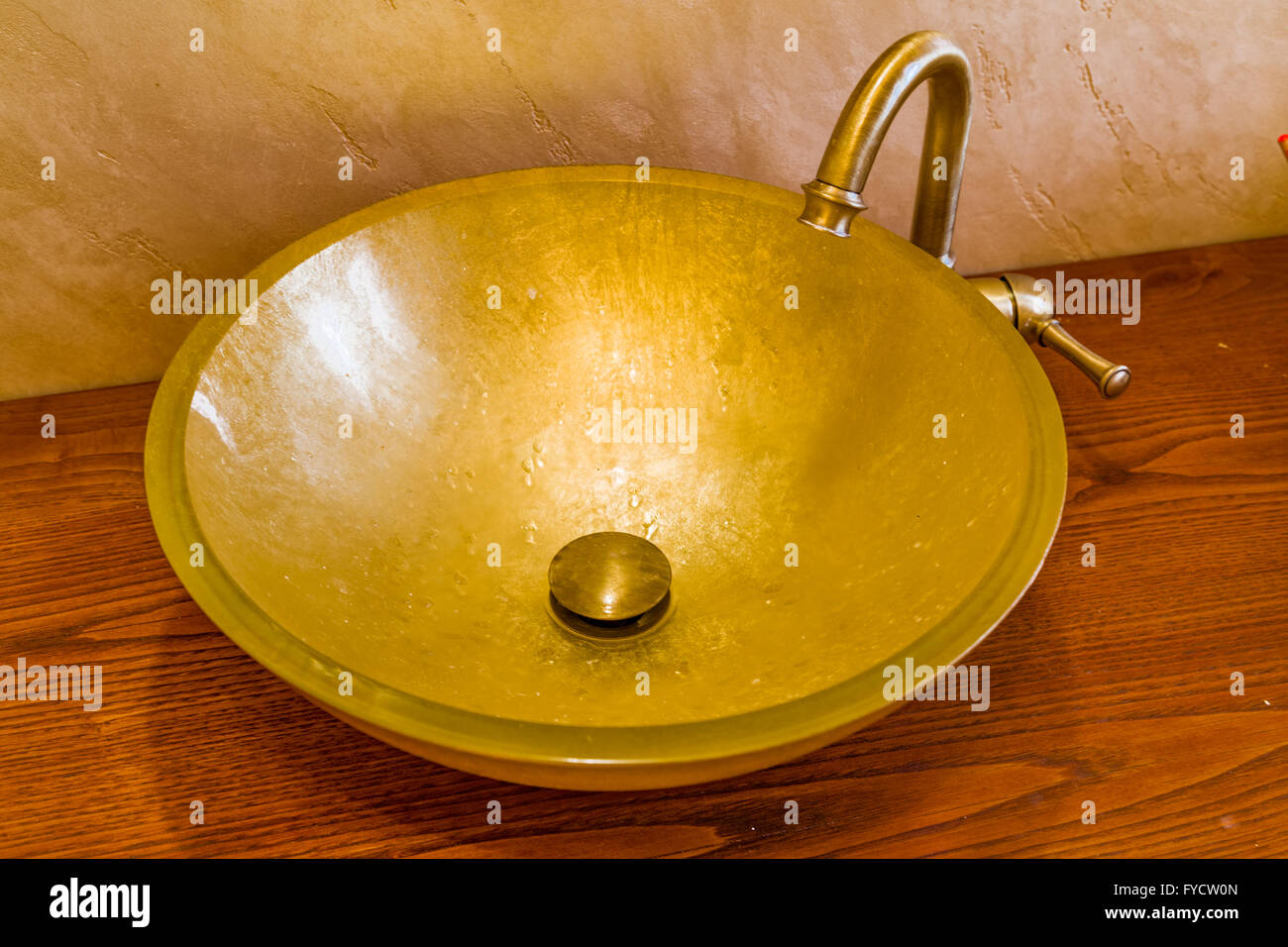 Waschbecken im goldenen Blatt aus gehärtetem Glas und Messing Wasserhahn Stockfoto