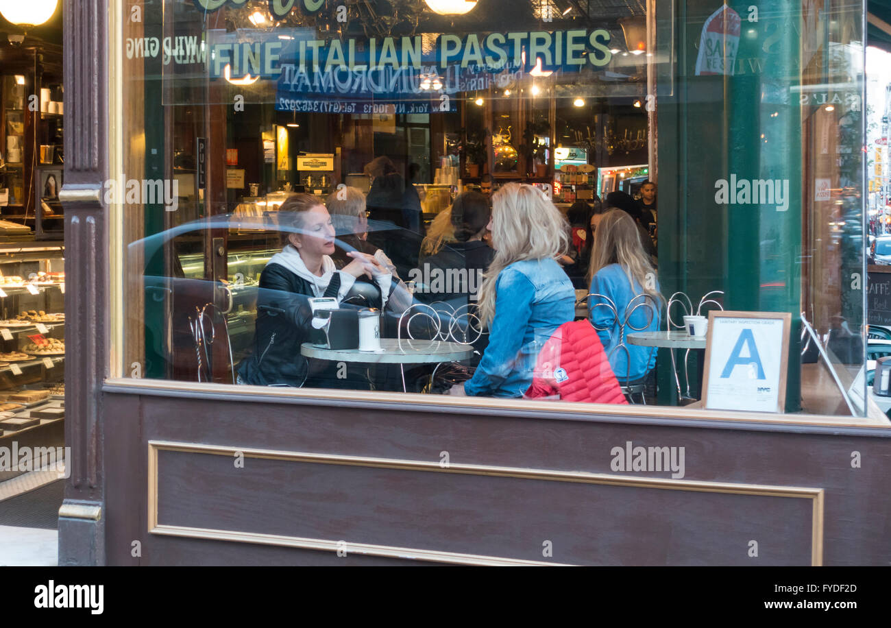 Zwei junge Frauen, die darauf warten, italienischen Kaffee und Gebäck im Caffe Roma in der Mulberry Street in Little Italy, New York City serviert werden Stockfoto