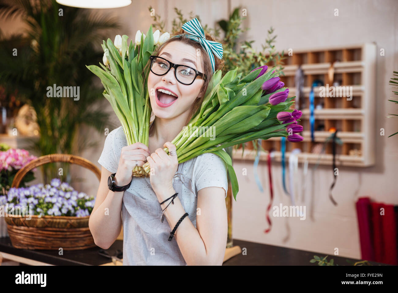 Lustige fröhliche junge Frau Floristen halten zwei Trauben von Tulpen im Blumenladen Stockfoto