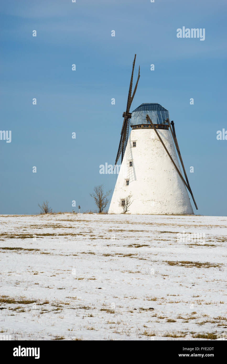 Alte Windmühle stehend im verschneiten Winter-Zeit-Feld gegen blauen Himmel Stockfoto