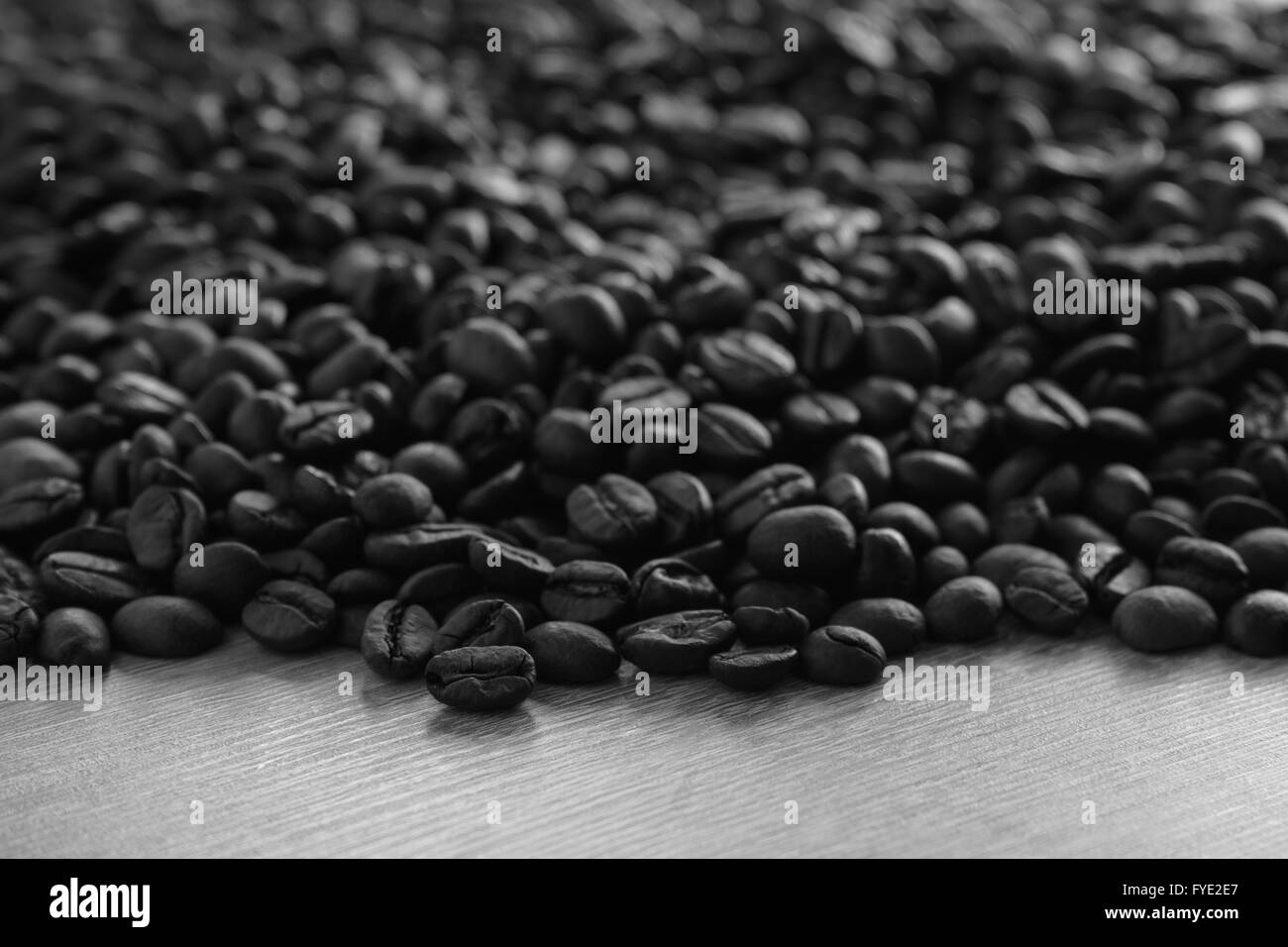 Abstrakte Closeup Kaffeebohnen auf hölzernen Hintergrund mit selektiven Fokus auf vorderen Bohnen, schwarz / weiß Bild Stockfoto