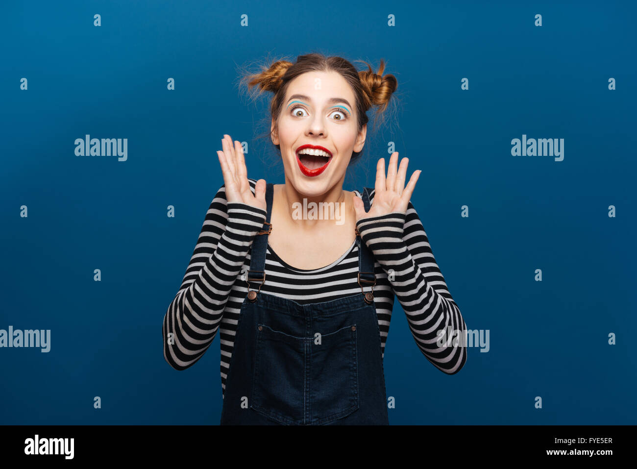 Überrascht fröhliche junge Frau lächelnd und schreien auf blauem Hintergrund Stockfoto