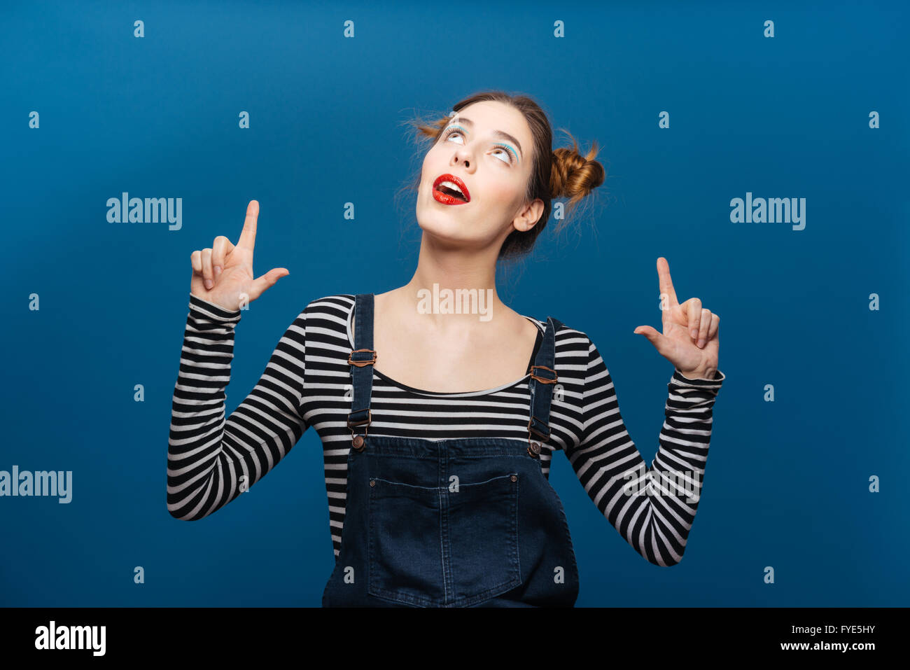 Glücklich süße junge Frau nach oben und nach oben mit beiden Händen auf blauem Hintergrund Stockfoto