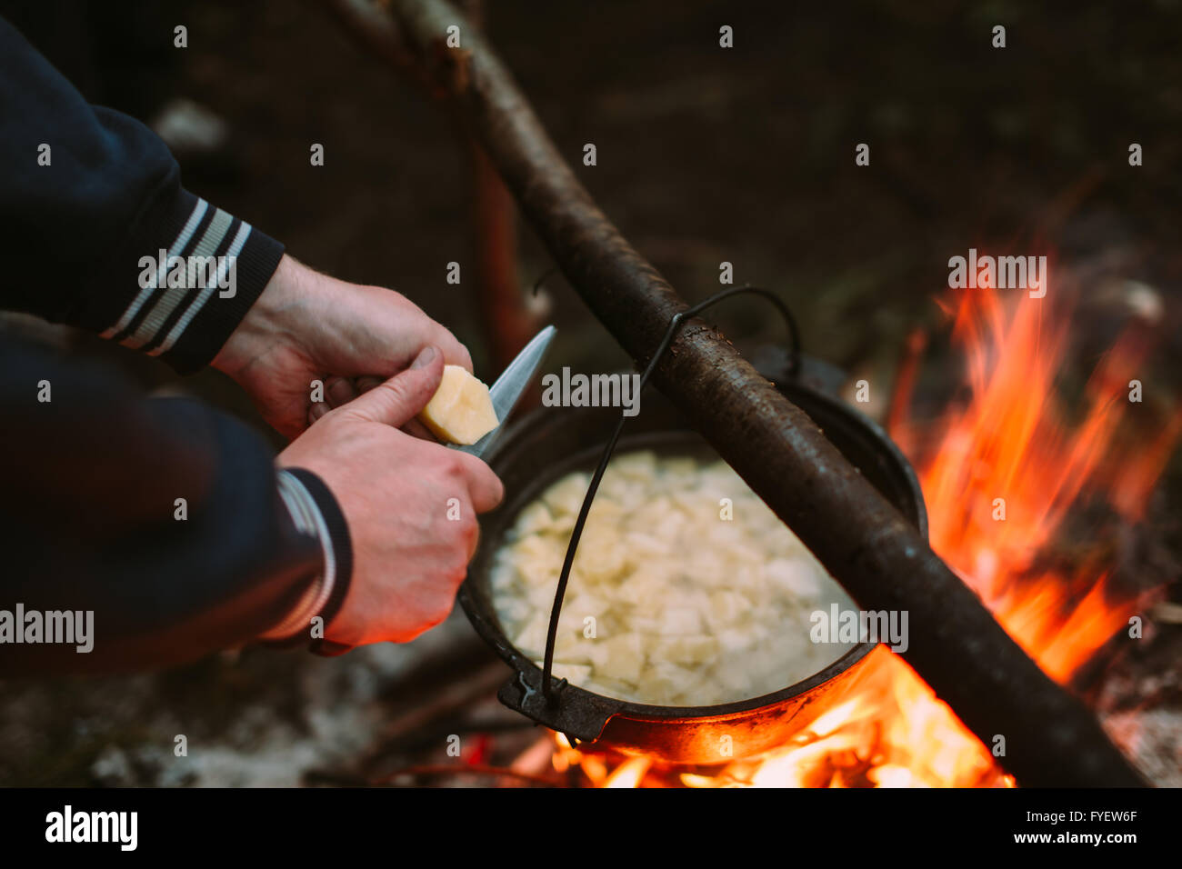 Fischsuppe Kochen am Feuer in der Natur und der menschlichen Hand geschnittene Kartoffeln in einer Pfanne. Stockfoto