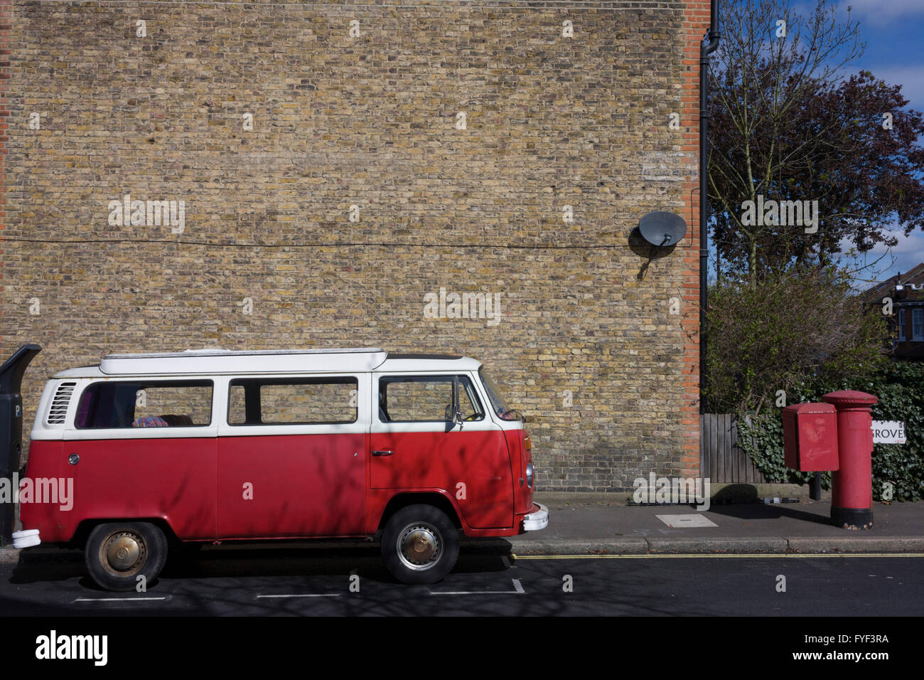 Abgestellten roten VW Wohnmobil geparkt neben einer verblichenen rot Royal Mail-Postfach in einer Wohnstraße in Herne Hill, London SE24. Stockfoto