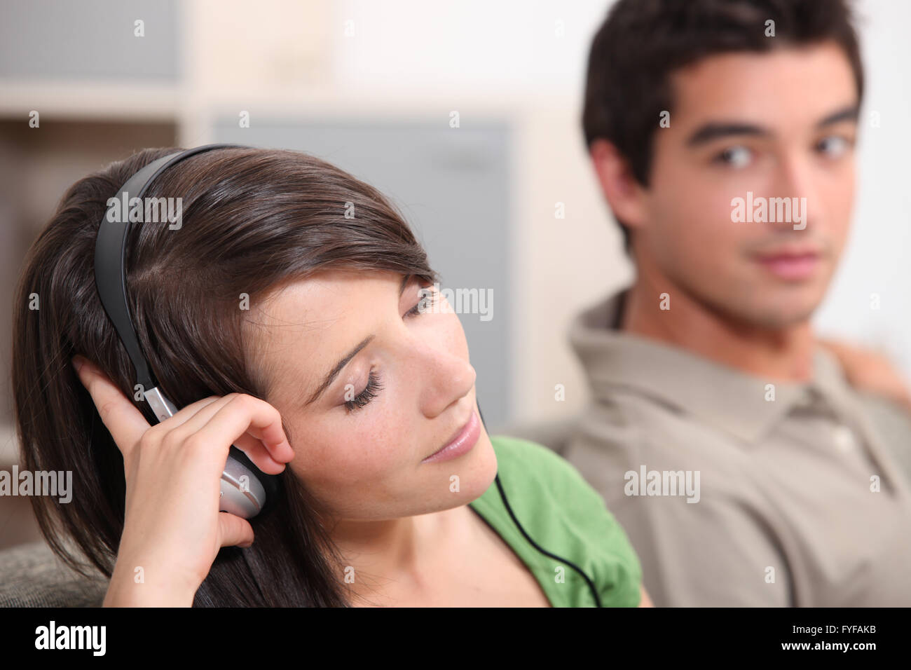 Anhören von Musik über Kopfhörer Freund beobachtete Frau Stockfoto