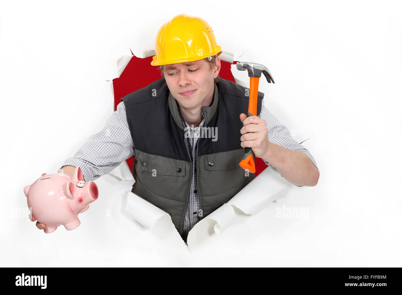 Bauarbeiter mit einem Hammer und einem Sparschwein Stockfoto