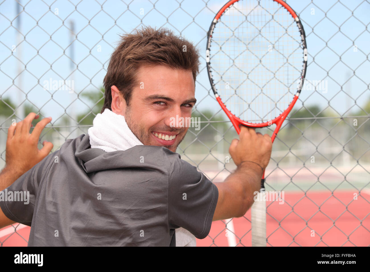 Lächelnde Tennisspieler stehend vor einem Amtsgericht Stockfoto