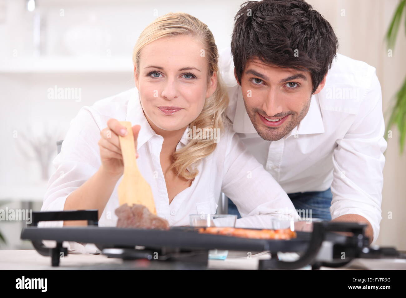 Paar, Kochen, Steak und Gambas auf einer Tischplatte Kochplatte Stockfoto