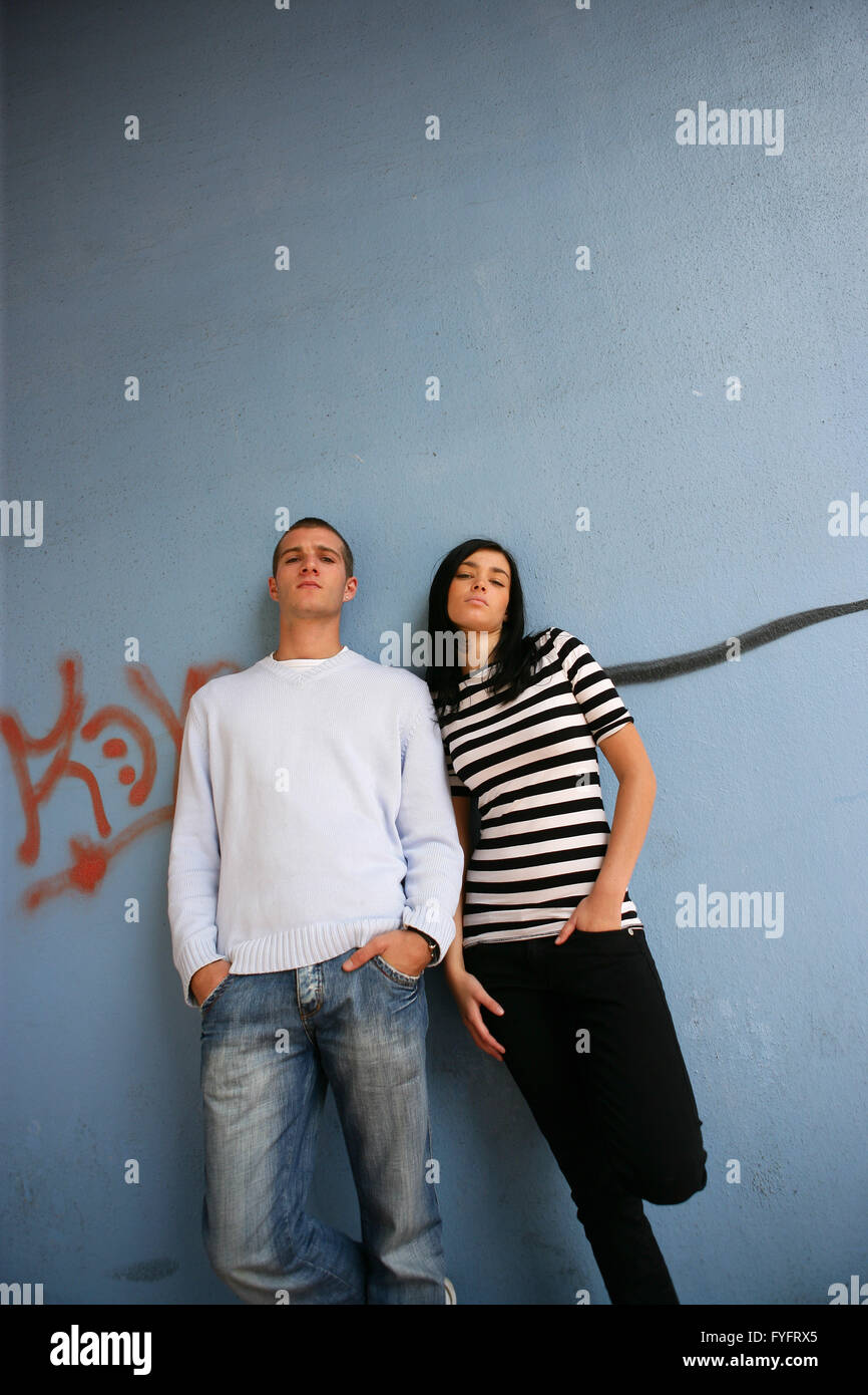 Junger Mann und junge Frau, die an eine Wand gelehnt Stockfoto