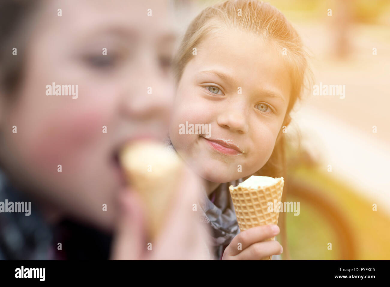 zwei Mädchen Eis essen im Freien bei sonnigem Wetter genießen Stockfoto