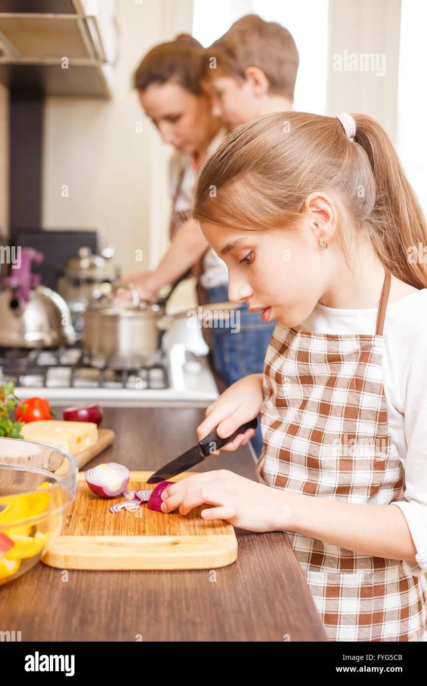 Familie kochen Hintergrund. Teen Mädchen schneiden Zwiebel auf Schneidebrett. Stockfoto