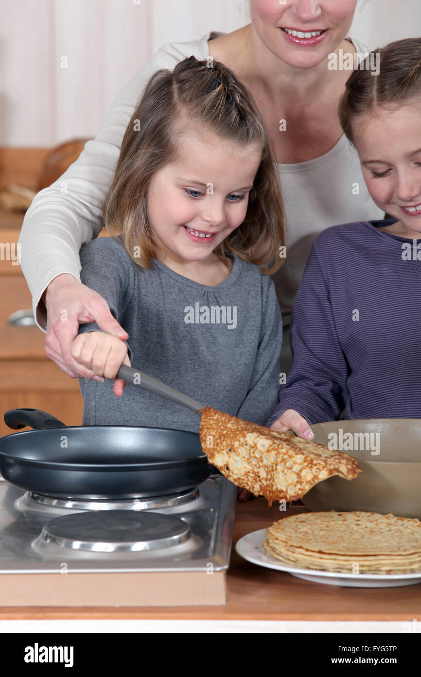 Mutter mit ihren beiden Töchtern Pfannkuchen zubereiten Stockfoto
