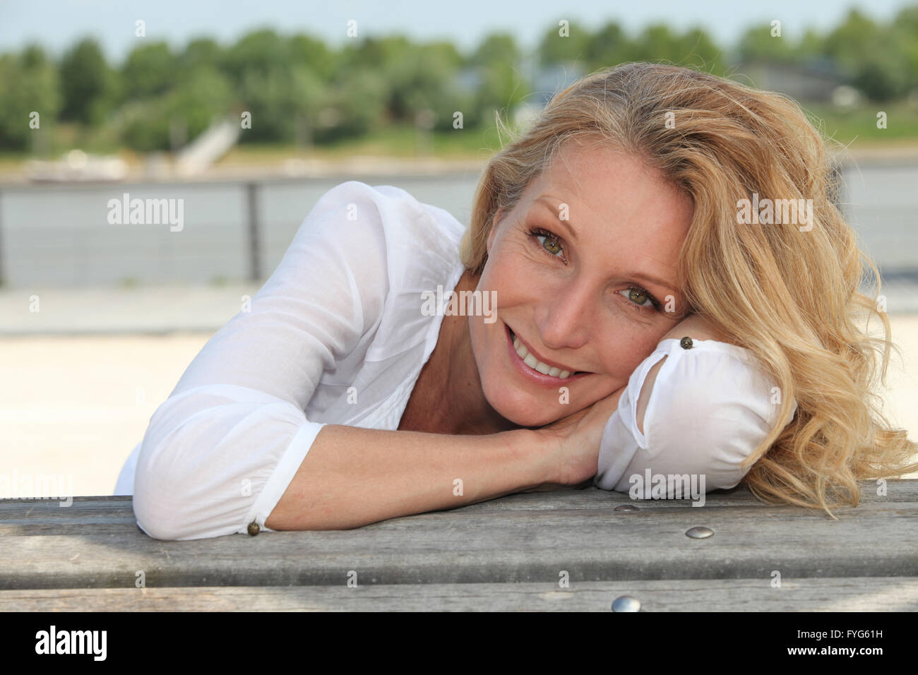 Entspannte glücklich Frau sitzt am Ufer Stockfoto