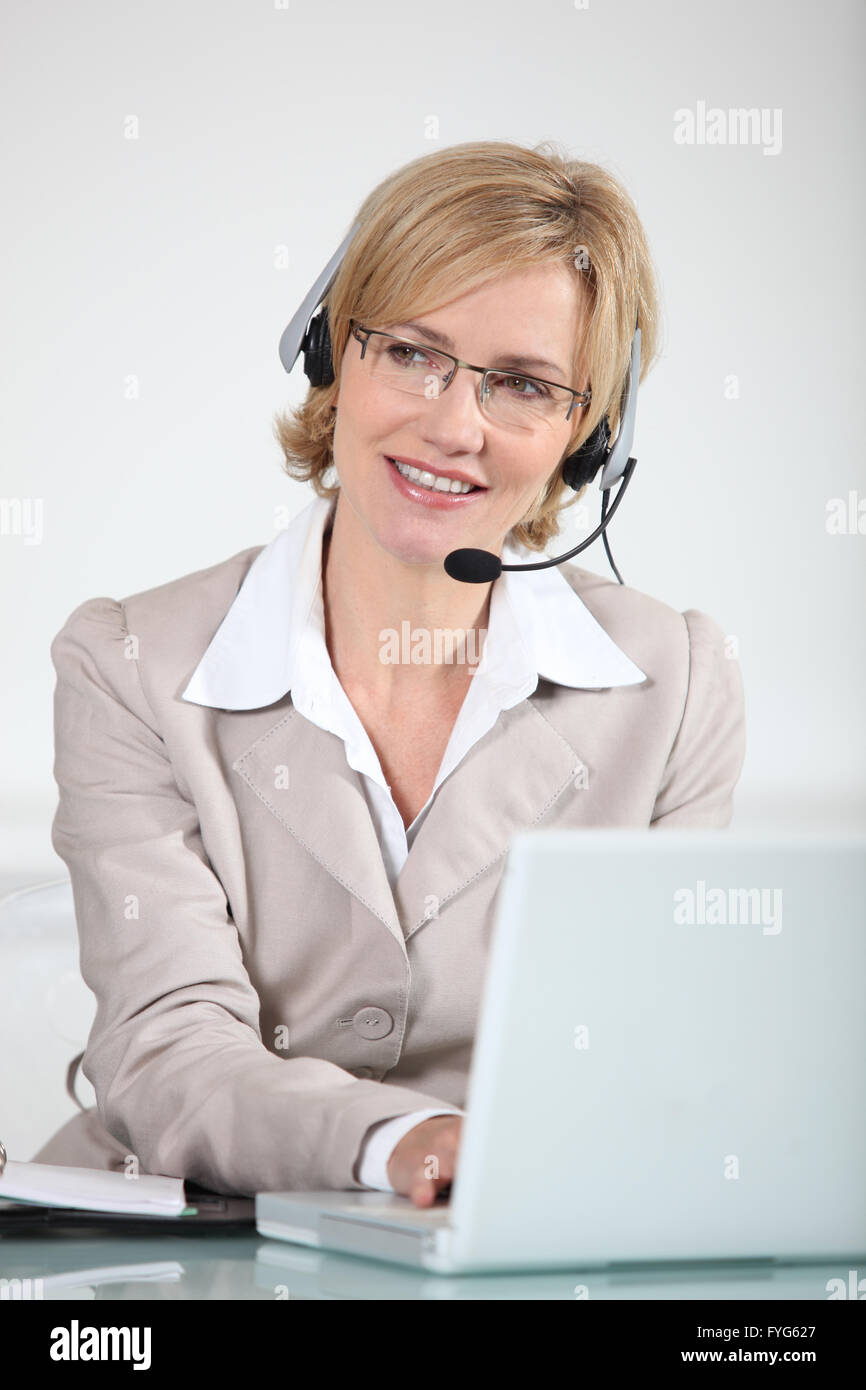 Frau mit einem Telefon-Kopfhörer an einem Laptopcomputer Stockfoto
