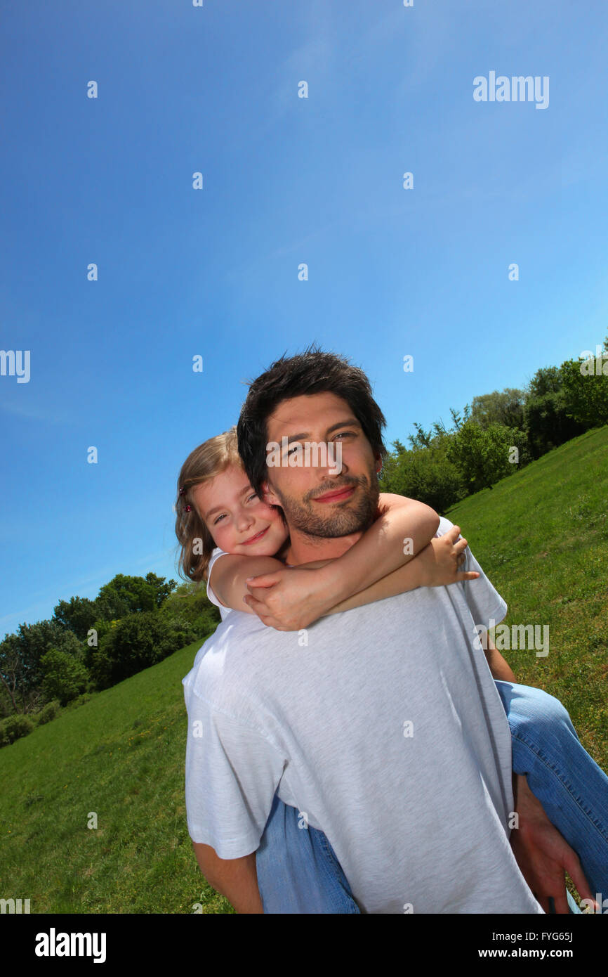 Mann mit Mädchen auf dem Rücken auf einer Wiese Stockfoto