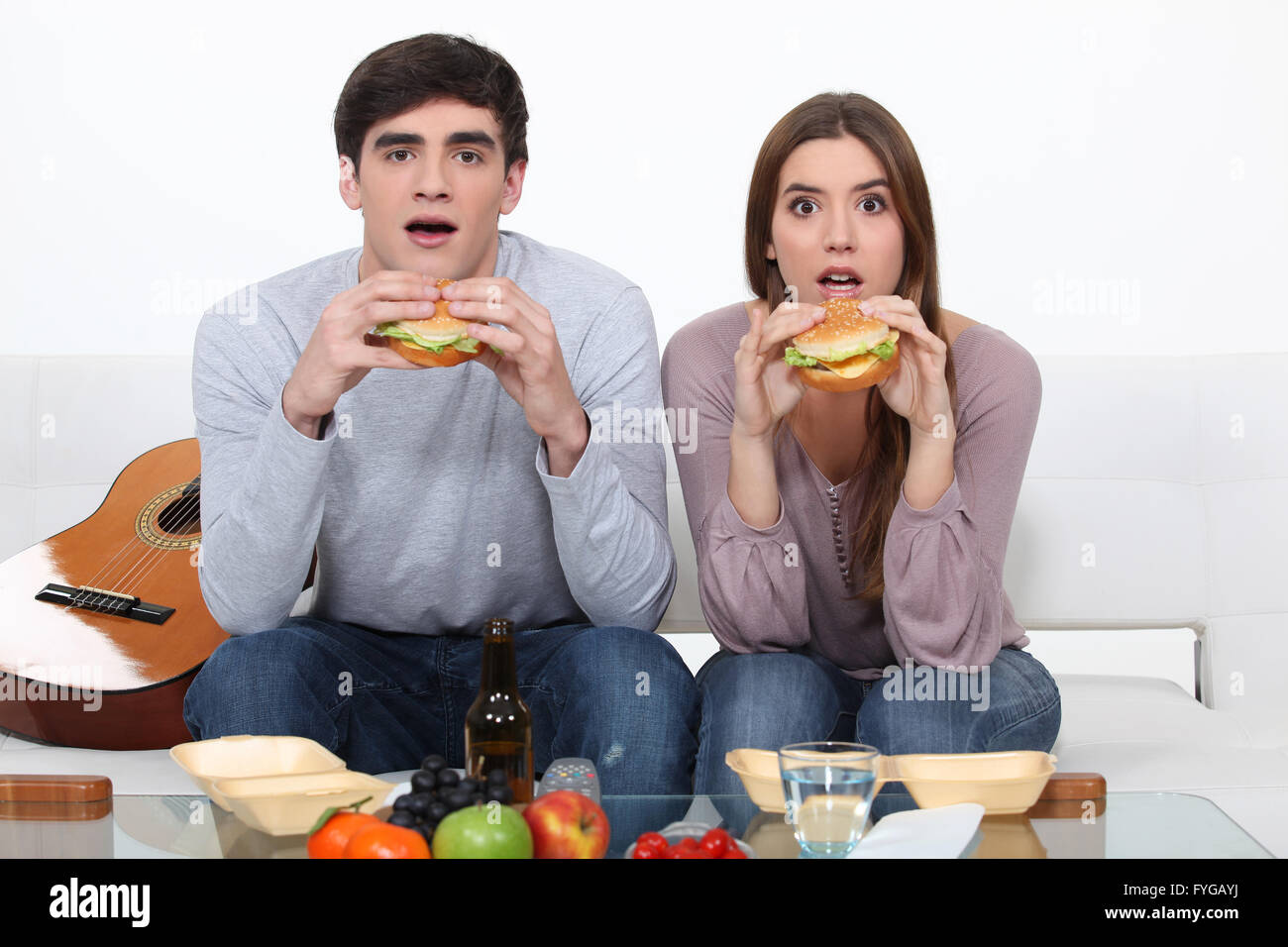 Zwei Studenten essen Burger und vor dem Fernseher Stockfoto