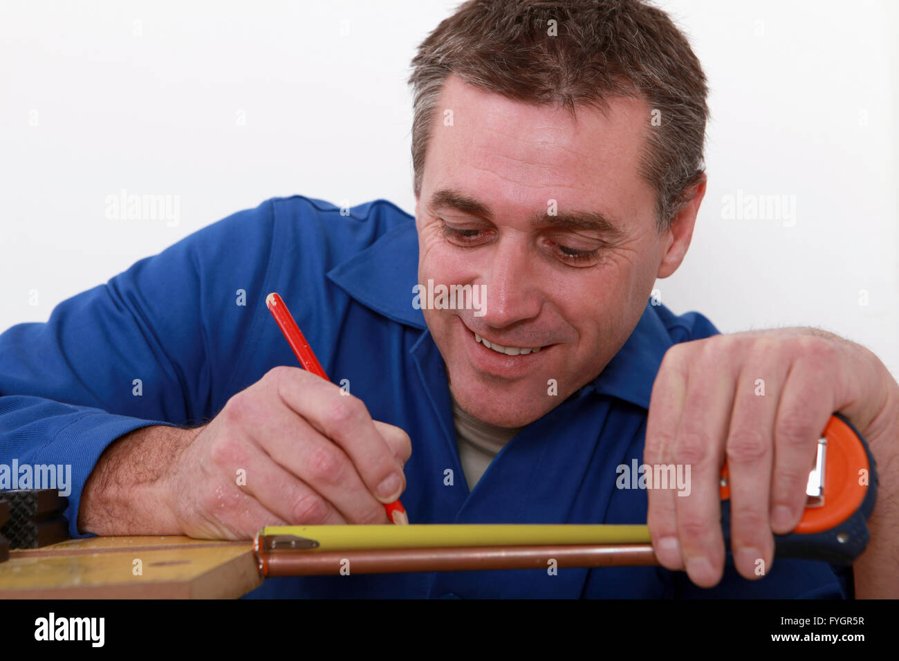 Handwerker, die Kennzeichnung einer Messung auf einem Kupferrohr Stockfoto