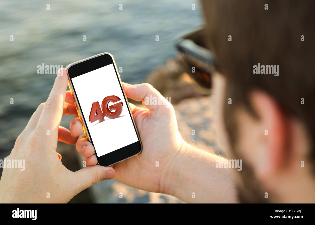 Mann an der Küste mit seinen 4g Smartphone. Alle Bildschirm-Grafiken bestehen. Stockfoto