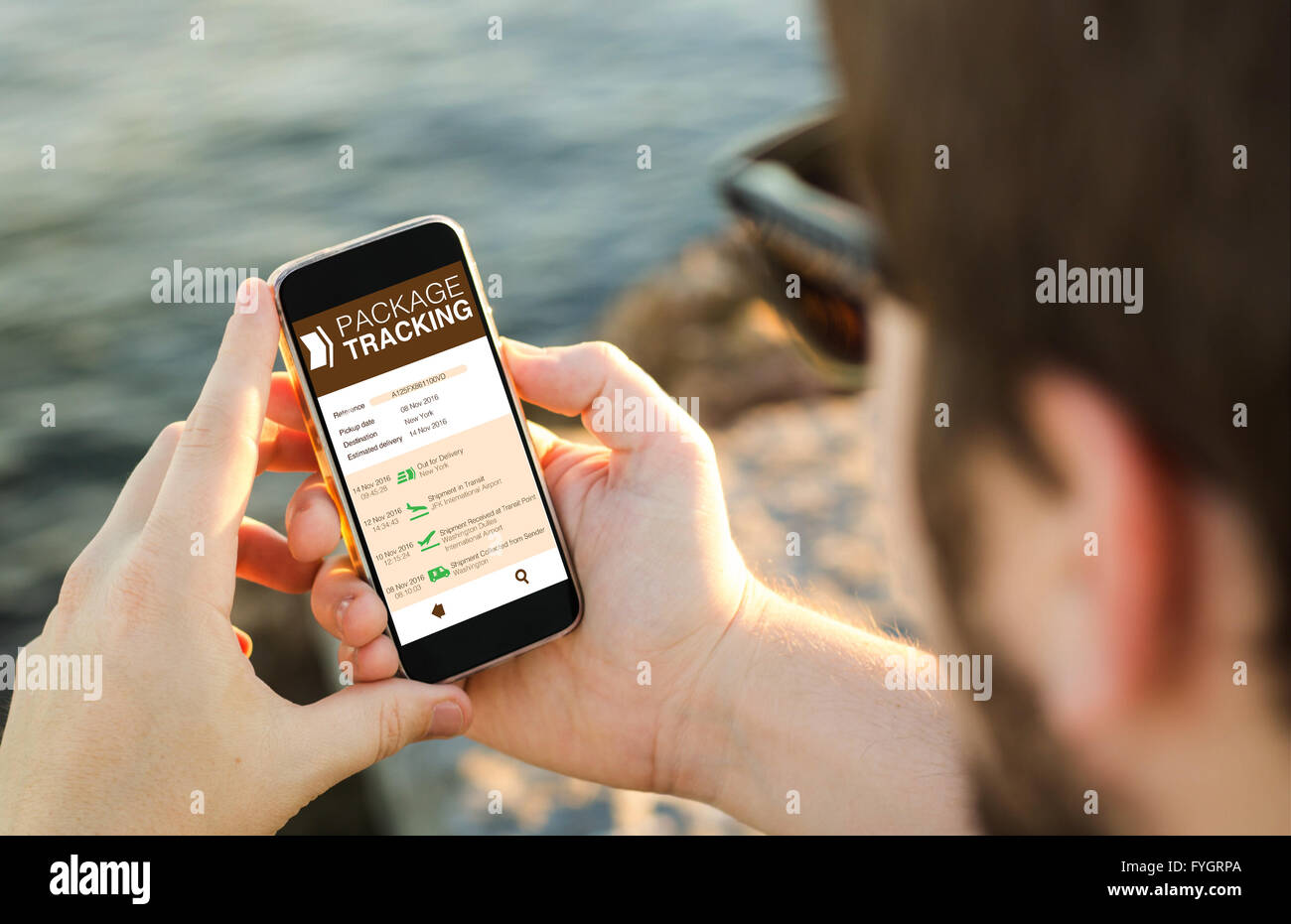 Mann an der Küste tracking-Paket auf einer Webseite auf seinem Smartphone. Alle Bildschirm-Grafiken bestehen. Stockfoto