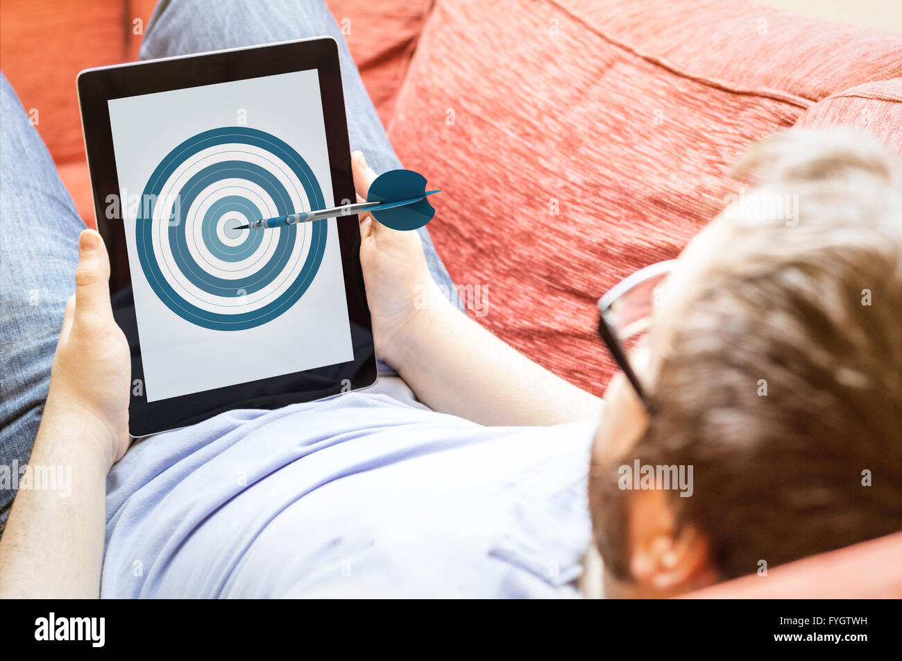 Genauigkeit, Geschäfts- oder mobile-marketing-Konzept: Hipster auf dem Sofa mit Dartscheibe Tablet. Die Bildschirmgrafik bestehen. Stockfoto Genauigkeit, Geschäfts- oder mobile-marketing-Konzept: Hipster auf dem Sofa mit Dartscheibe Tablet. Die Bildschirmgrafik bestehen. Stockfoto