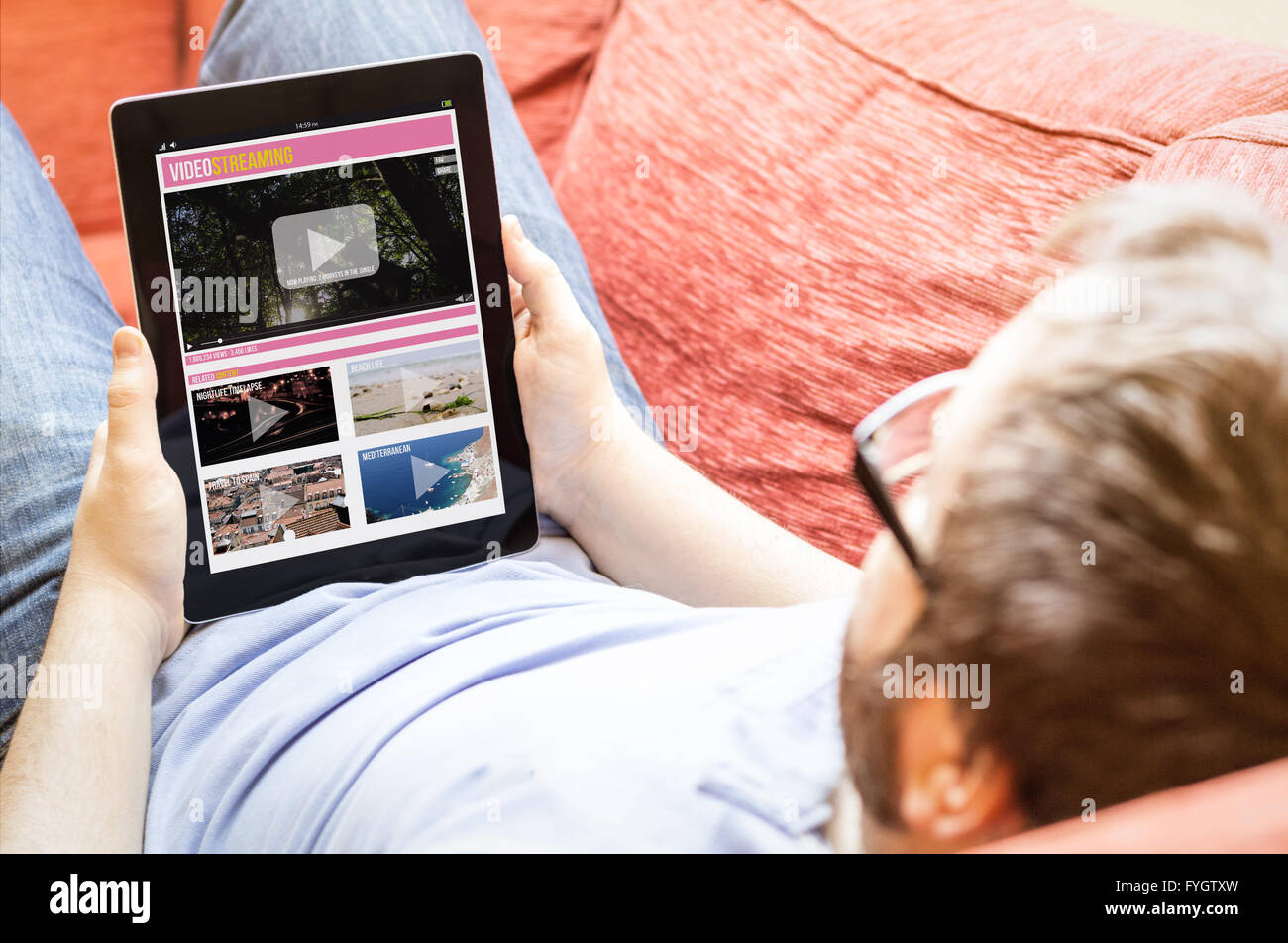 Technologie-Lifestyle-Konzept: Hipster auf dem Sofa mit Video-Streaming-Tablet. Die Bildschirmgrafik bestehen. Stockfoto
