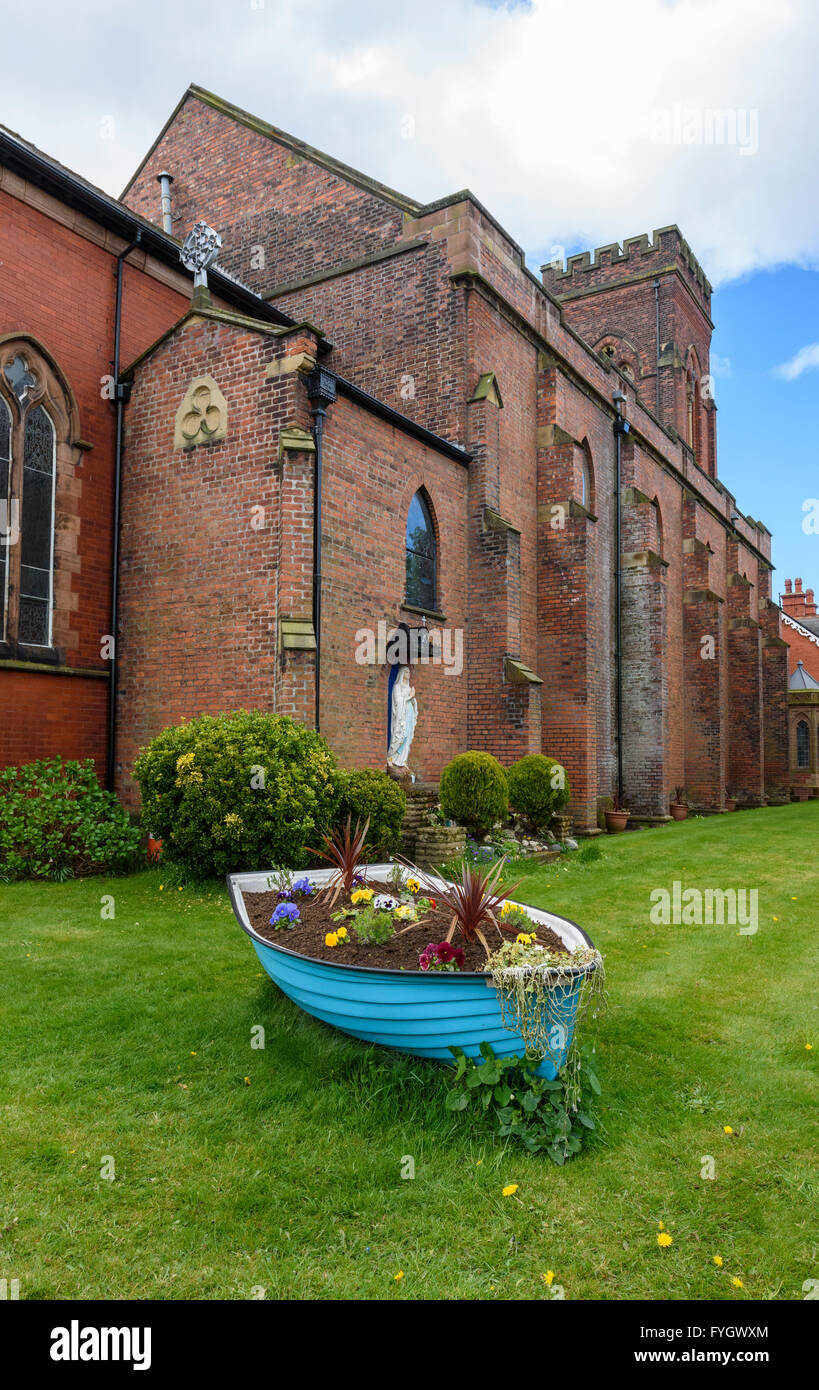 Altes Ruderboot umgewandelt in ein Blumenbeet außerhalb einer Kirche in Lytham, Lancashire, UK Stockfoto