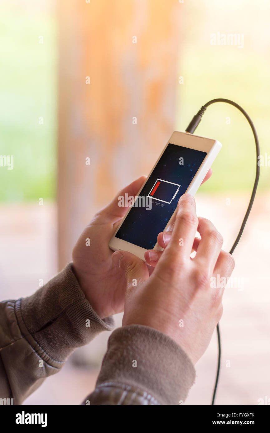 Hände des Jünglings Smartphone mit schwacher Batterie hält. Alle Bildschirm-Grafiken bestehen. Stockfoto