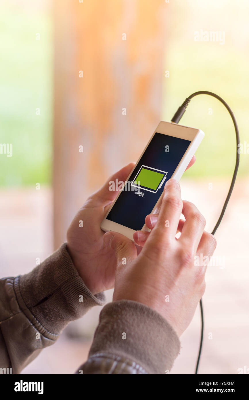 Hände des Jünglings Smartphone mit vollem Akku hält. Alle Bildschirm-Grafiken bestehen. Stockfoto