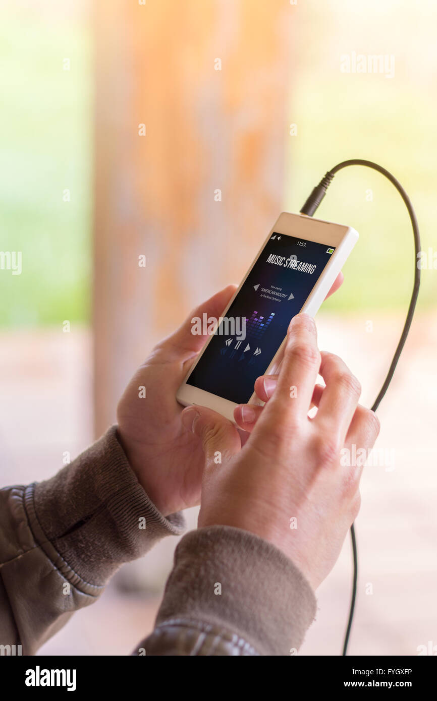 Hände des Jünglings holding Smartphone mit Musik-Streaming-app. Alle Bildschirm-Grafiken bestehen. Stockfoto