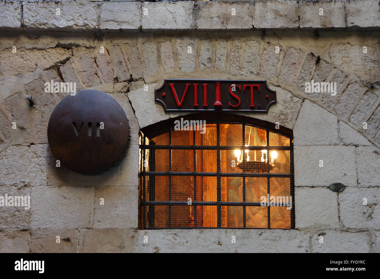 Vergittertes Fenster leuchtete aus innerhalb mit einem Kandelaber Stockfoto