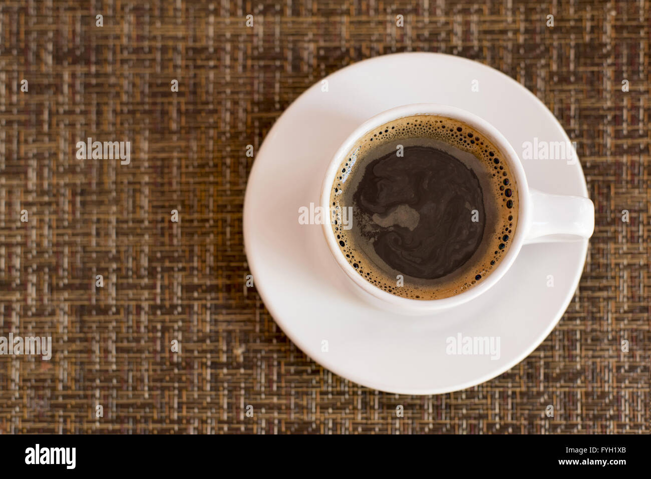 Draufsicht der dunklen Kaffee in weiße Becher und Teller auf Tabellenhintergrund Wicker Textur. Stockfoto