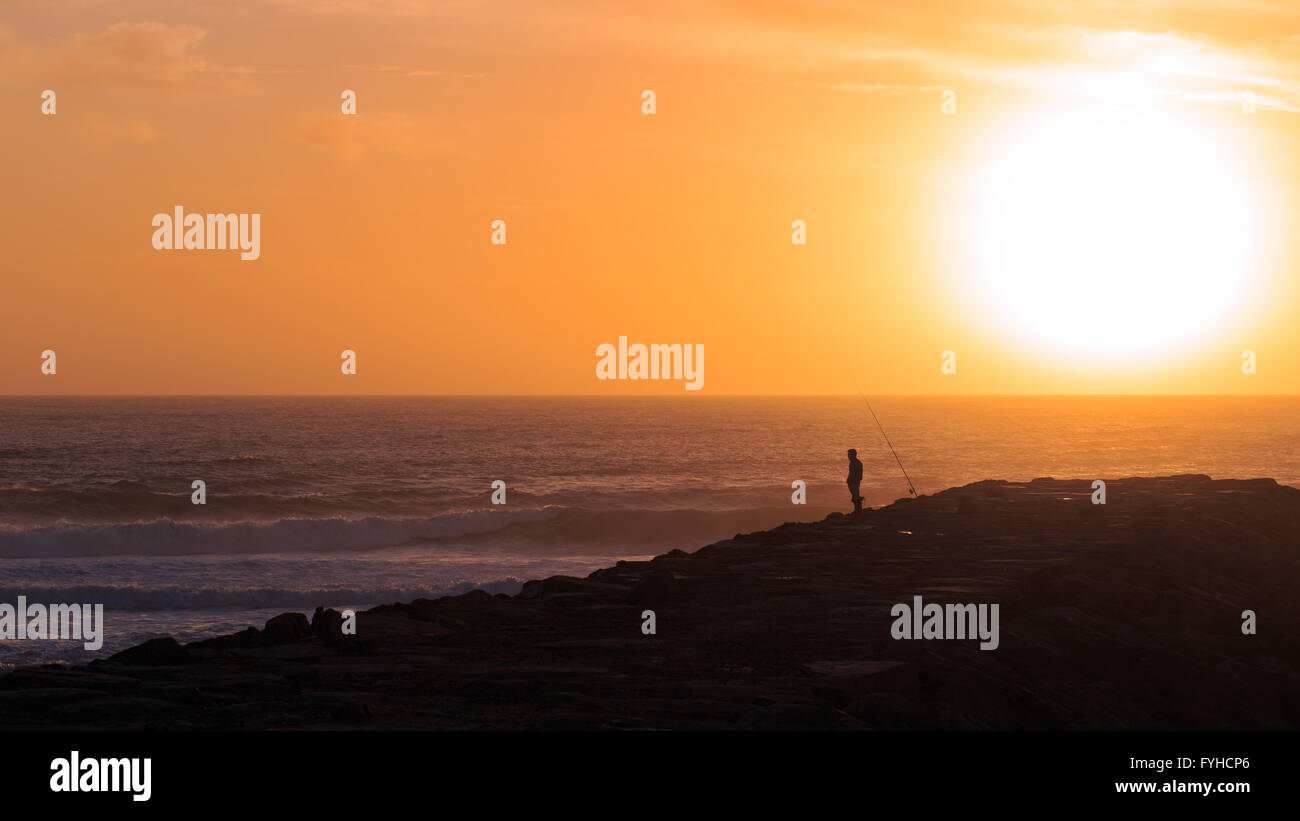 Silhouette der Fischer steht ein Wellenbrecher Stein am Foradouro Strand, Portugal. Stockfoto