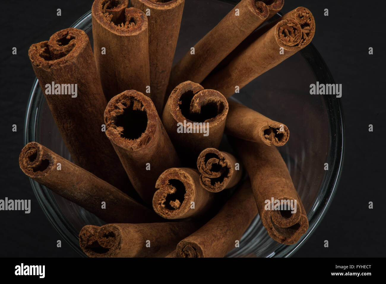 Top View Zimt Sticks stehen in Glasschale mit schwarzem Schiefer Schneidbrett im Hintergrund Stockfoto