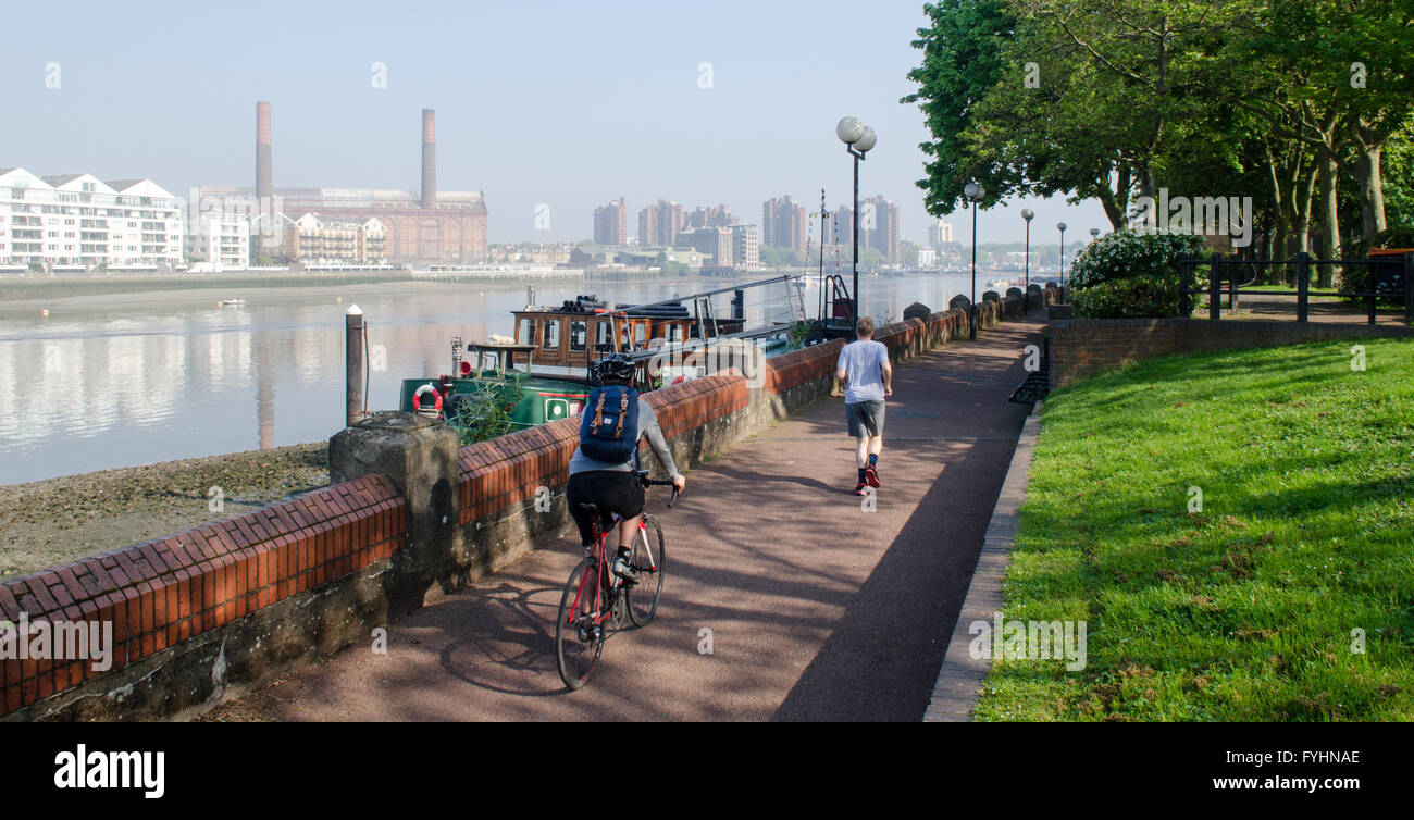 Nicht identifizierbare Radfahrer und Jogger auf einem Pfad an der Themse in Battersea, London. Stockfoto