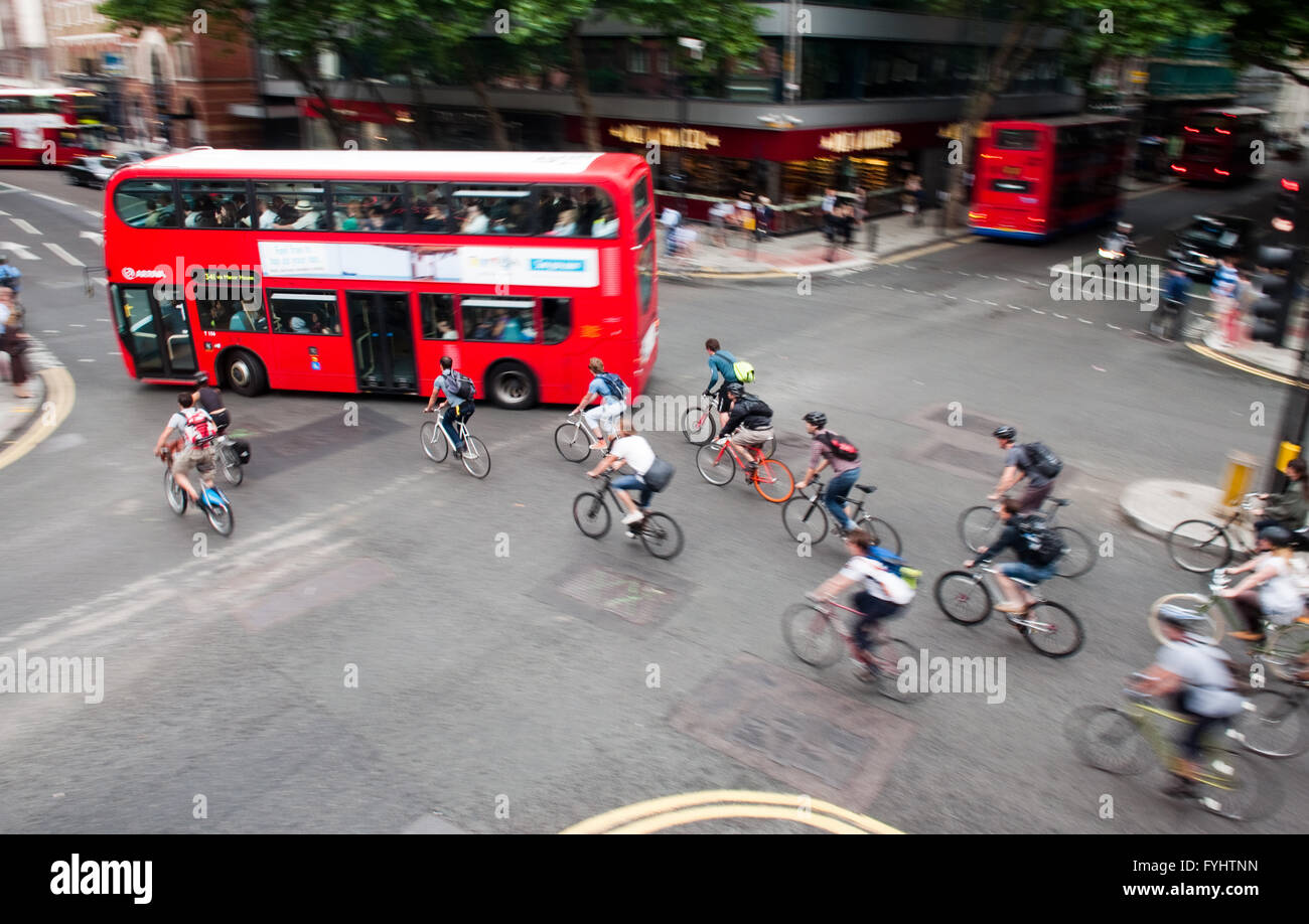 Eine Gruppe von Radfahrern Pendler auf den Weg von ein grünes Licht an einer belebten Straßenkreuzung im Zentrum von London. Stockfoto