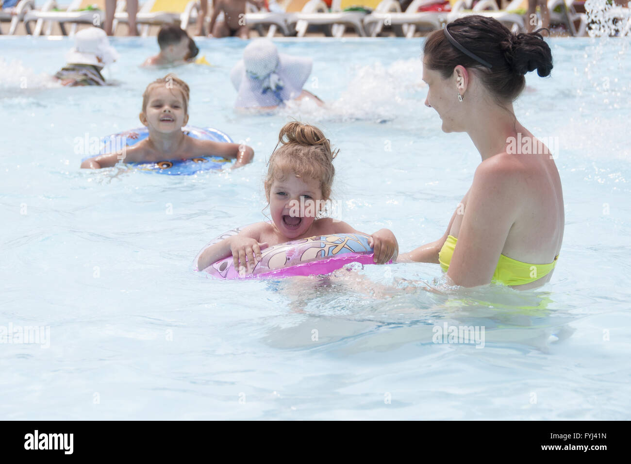 Mutter und zwei Töchter sind in einem öffentlichen Schwimmbad schwimmen. Stockfoto