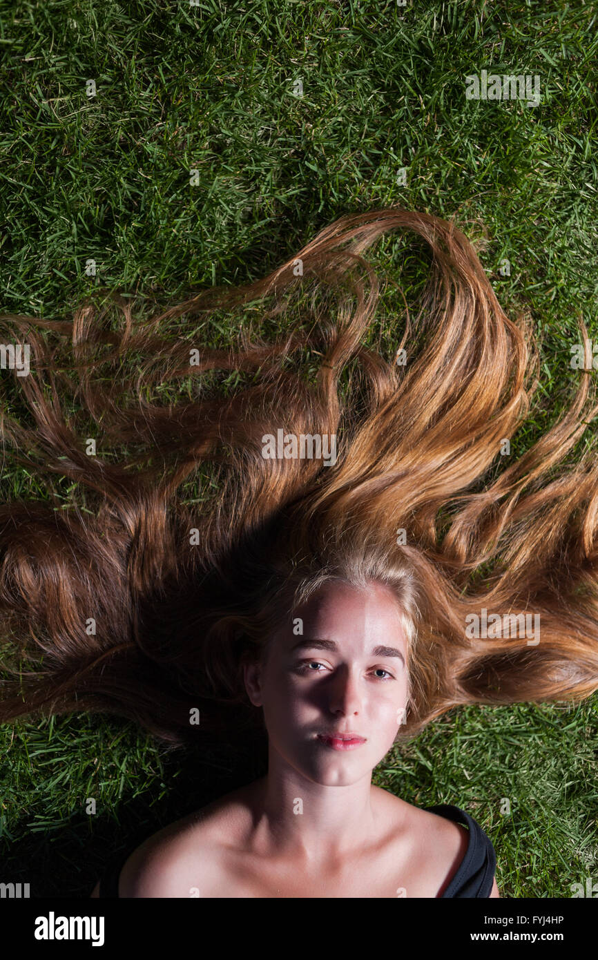 schönes junges Mädchen liegt auf dem grünen Rasen Stockfoto