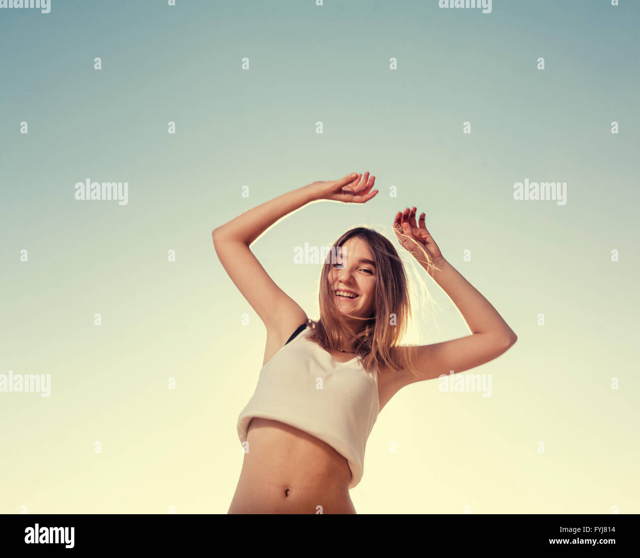 Blonde Teenager Mädchen glücklich mit dem blauen Himmel in den Rücken springen Stockfoto
