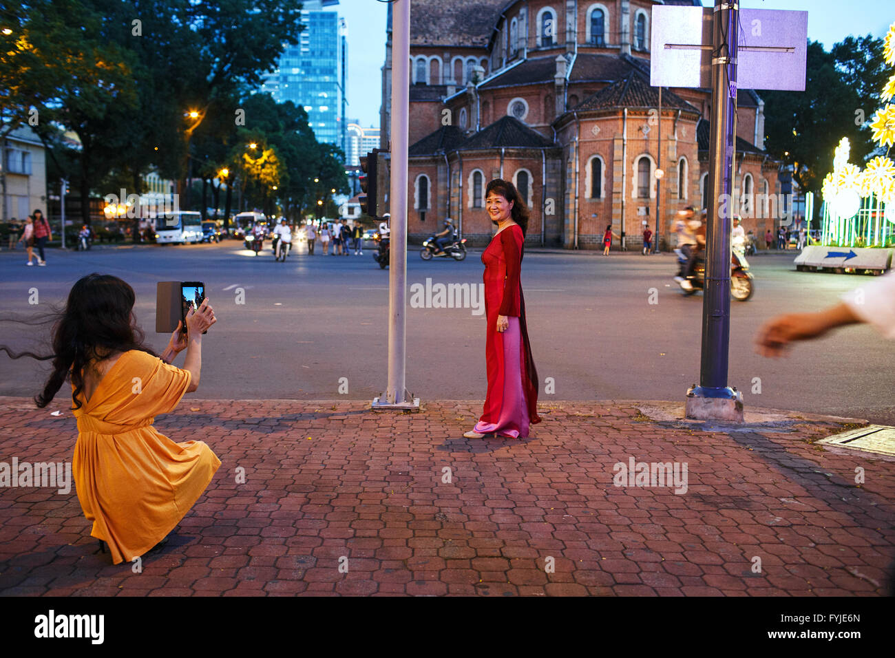 Frauen nehmen Fotos hinter der Kathedrale Notre Dame in Ho Chi Minh City, Vietnam Stockfoto